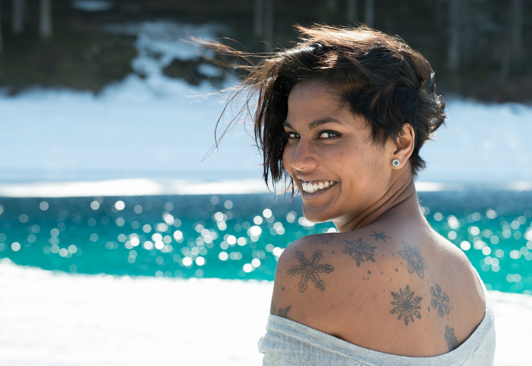 Woman with tattoos looking over her shoulder, smiling